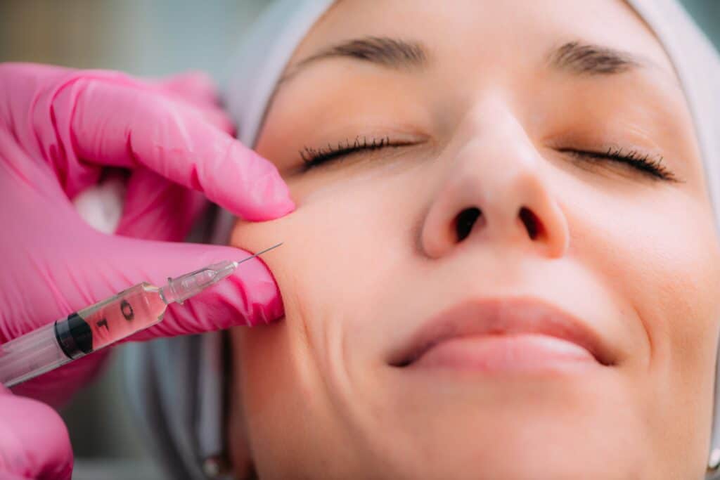 woman smiling as a nurse injects Juvederm into her cheek