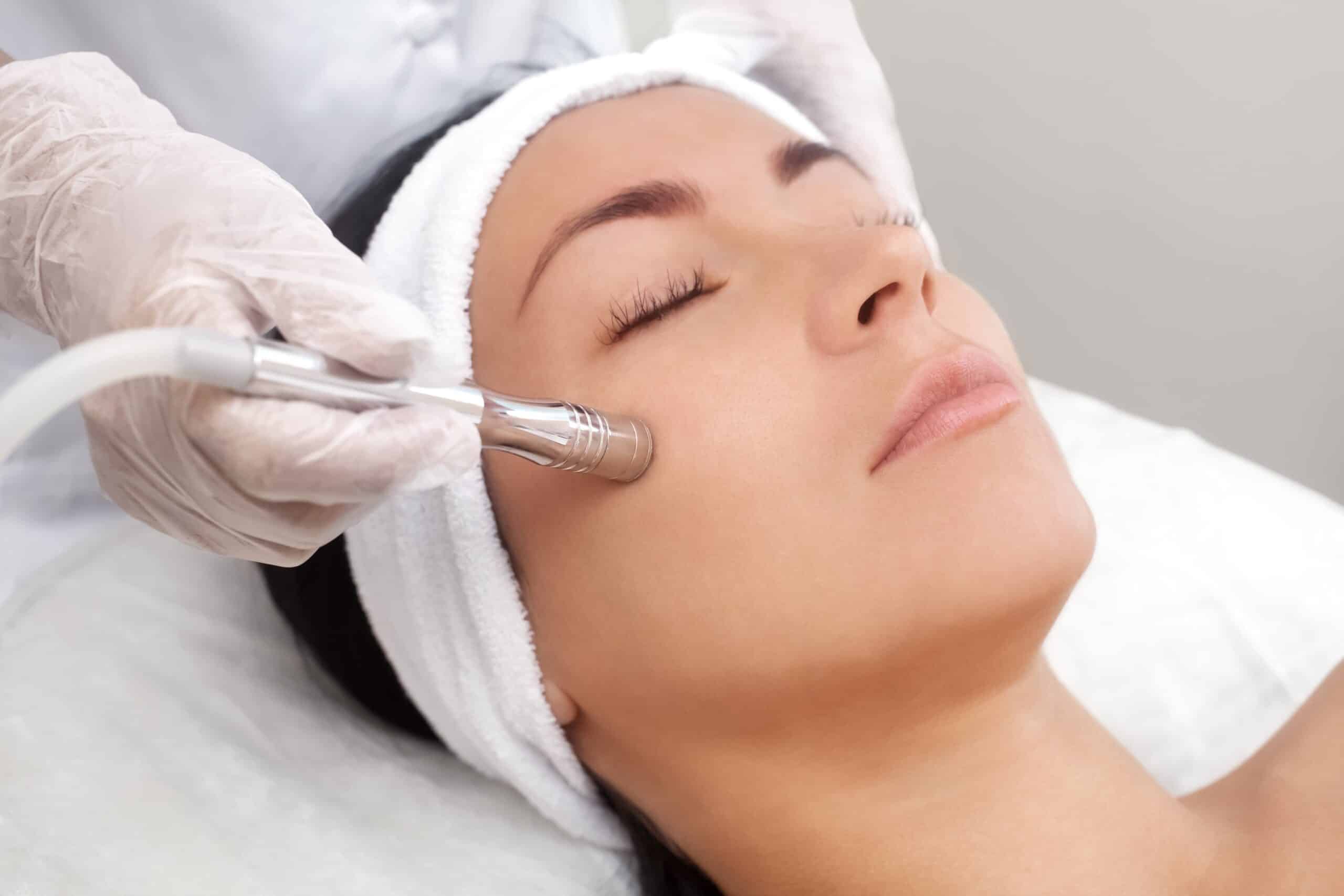 provider using a microdermabrasian tool on a young woman's face